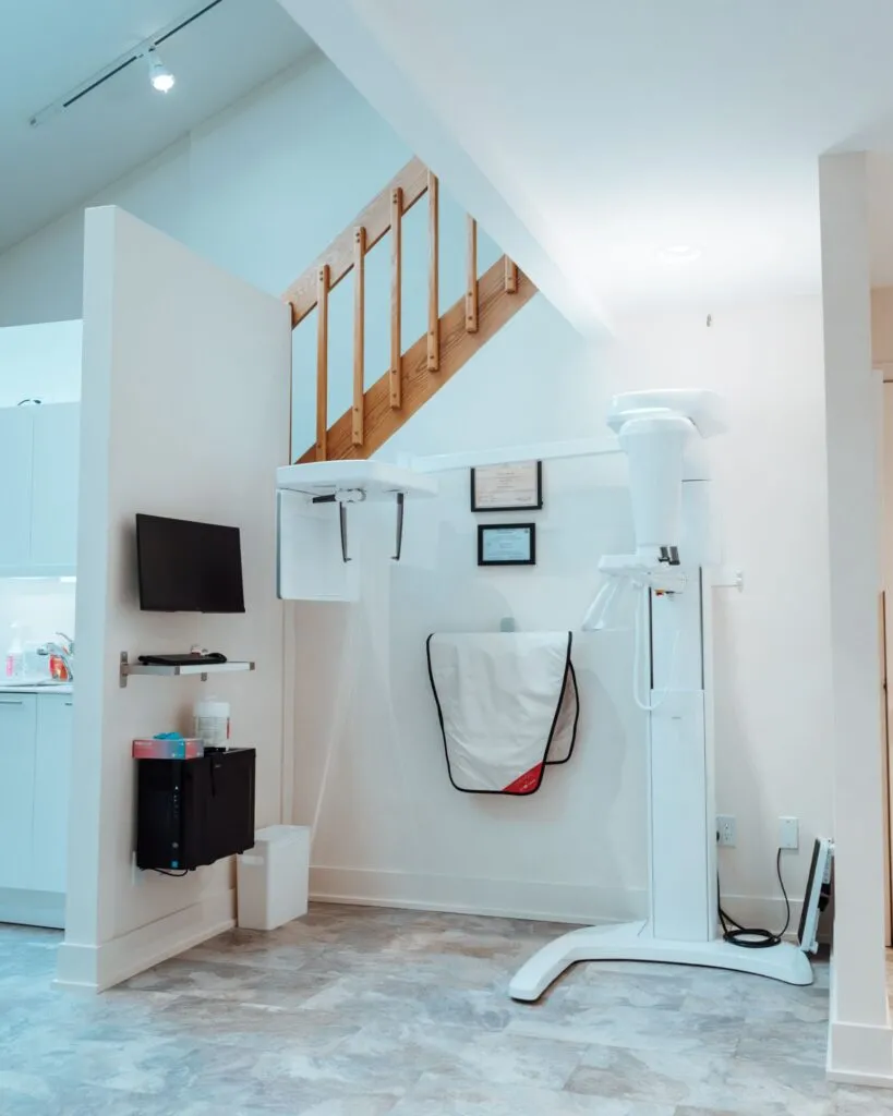 Orthodontic treatment area featuring a digital x-ray machine, wall-mounted TV, and dental supplies, designed for patient comfort at Smile Orthodontics by Dr. Sarah.
